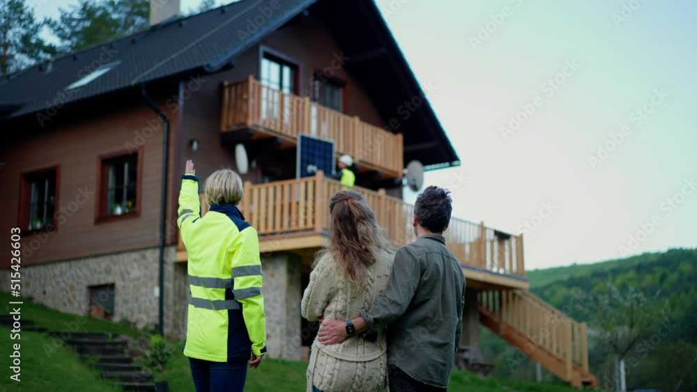 Woman engineer talking to couple about solar panel installation in front of their house. Woman engineer talking to couple about solar panel installation in front of their house.