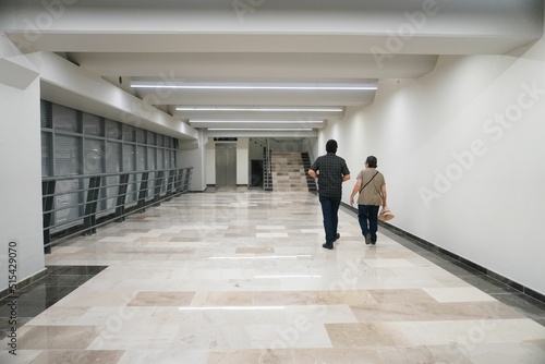 Back shot of two men walking inside a modern corridor in AIFA Airport in Mexico with elegant lights photo