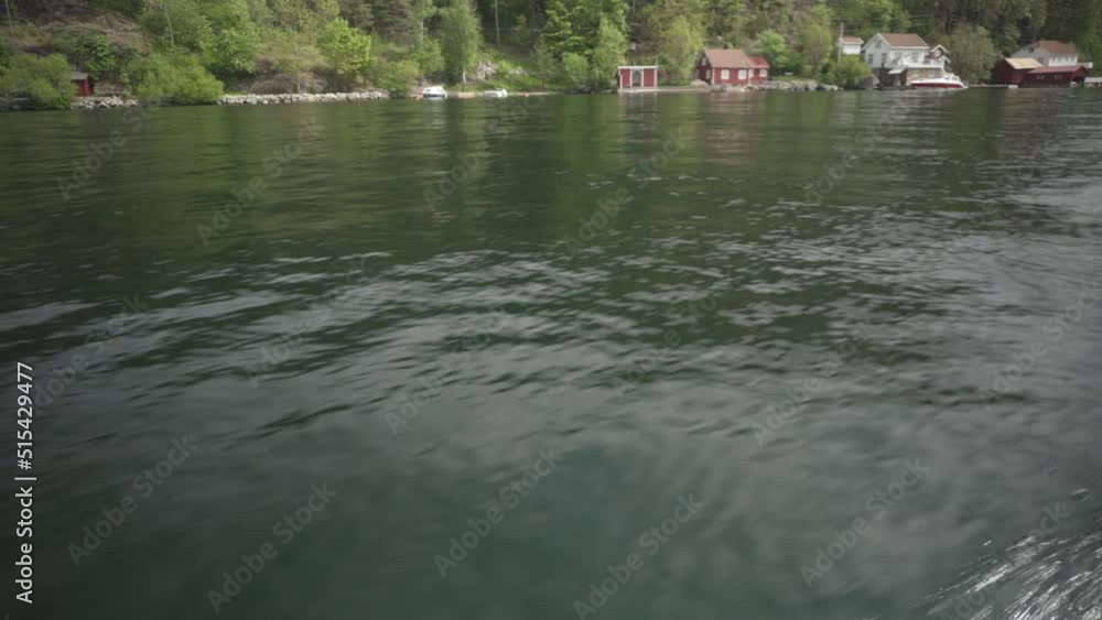 Point Of View Of A Sailing Boat On Tranquil Lake With Traditional Wooden Houses By The Shore In Norway. POV Point Of View Of A Sailing Boat On Tranquil Lake With Traditional Wooden Houses By The Shore In Norway. POV