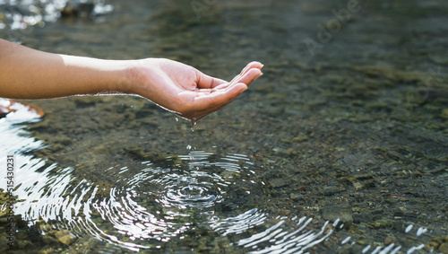 Man's hand touching water in the midst of nature