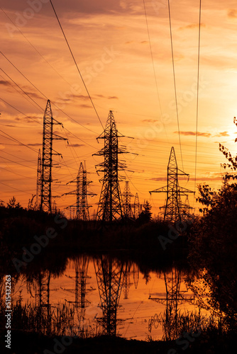 High voltage pole on silhouette summer sunset background.