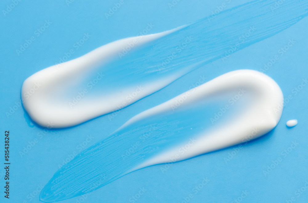 A sample of white moisturizer on a blue background. Cosmetic product for the skin. A sample of white moisturizer on a blue background. Cosmetic product for the skin.