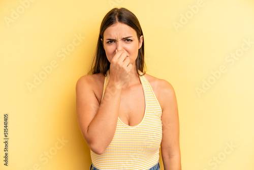 young adult pretty woman feeling disgusted, holding nose to avoid smelling a foul and unpleasant stench