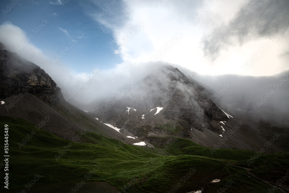 Mountain peaks in the fog of an upcoming storm with a green valley underneath in the alps of the Allgäu in Germany