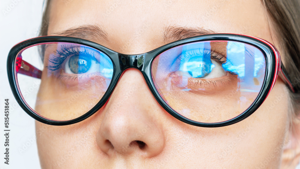 Portrait of a young caucasian woman with stylish female glasses for working at a computer with a blue filter lenses isolated on a white background. Anti blue light and rays. Eye protection - obrazy, fototapety, plakaty 