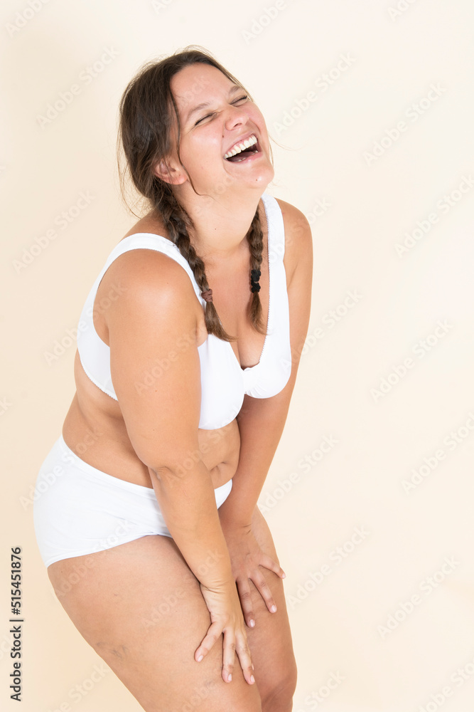 Obraz premium Plus size girl in lingerie with two braids smiling and showing off her body. proud of her body