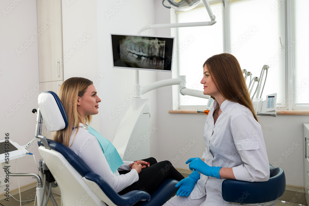 She is sitting in the dentist's chair. The dentist explains and advises the patient. She is sitting in the dentist's chair. The dentist explains and advises the patient.