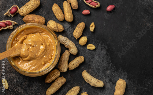 Εκτύπωση καμβά Peanut butter or paste in an open jar and peanuts in the peel scattered on a dar