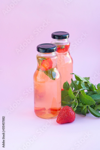 Homemade strawberry mint lemonade in two glass bottles to go. Eco packaging, reusable dishes zero waste concept. Natural healthy alcohol free drink recipe for hot summer on pink background