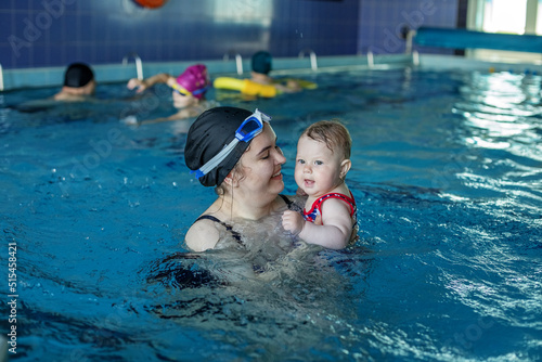 Foto Smiling happy mother with baby girl in swimming pool