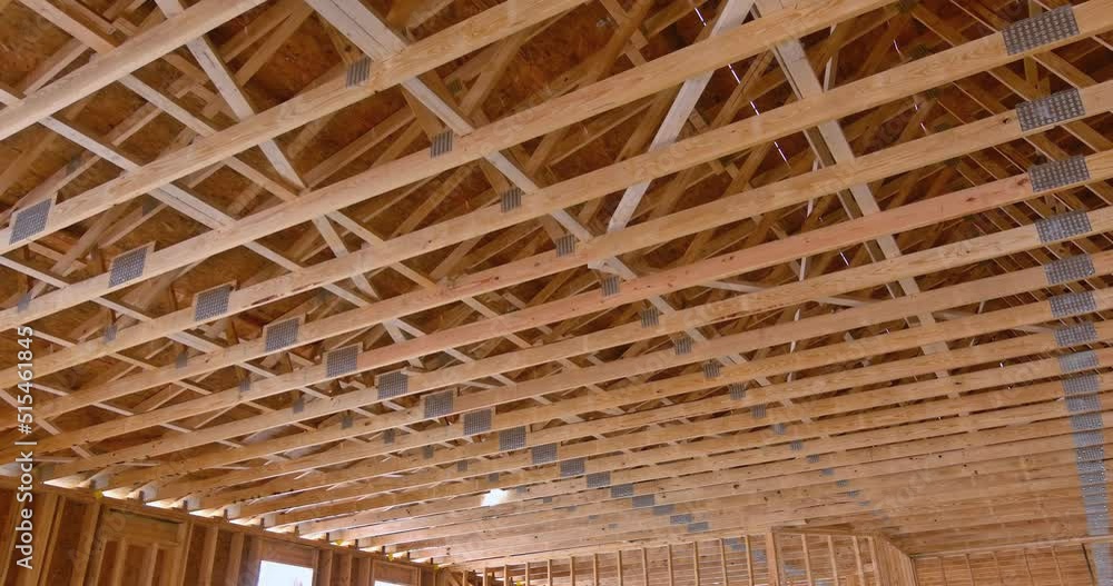 Construction of wooden building, an interior view of wood beams framework under construction with wooden truss rafters Construction of wooden building, an interior view of wood beams framework under construction with wooden truss rafters