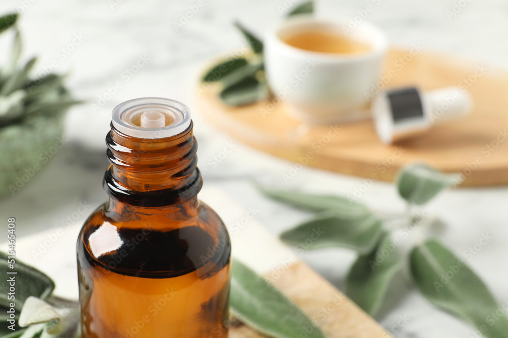 Bottle of essential sage oil and leaves on table, closeup. Space for text Bottle of essential sage oil and leaves on table, closeup. Space for text