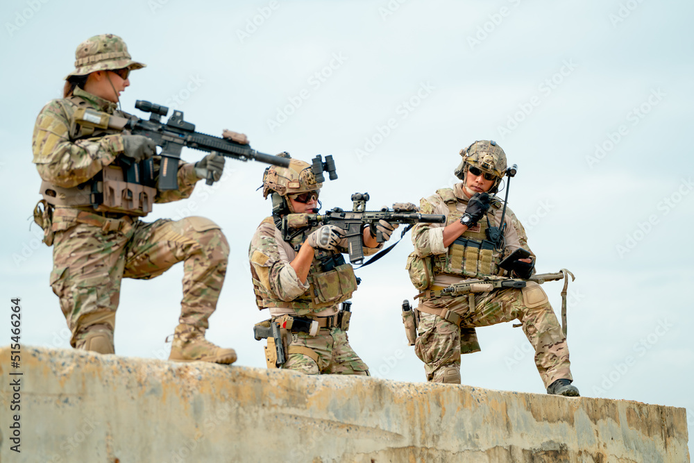 Fototapeta premium Military or soldier team with gun stay on concrete wall and prepare for battle with enemy in field with day light.