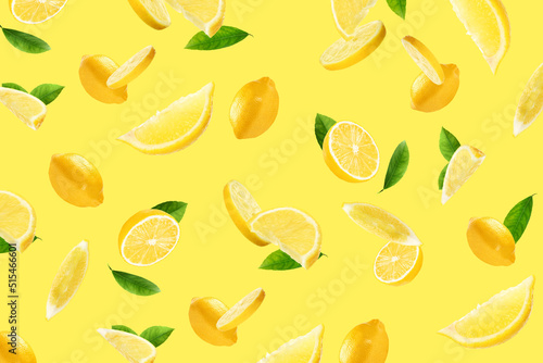 Fresh ripe lemons and green leaves flying on yellow background