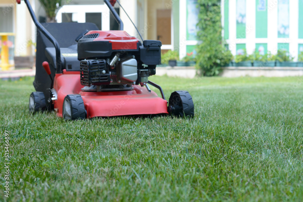 Modern garden lawn mower on green grass in park Modern garden lawn mower on green grass in park