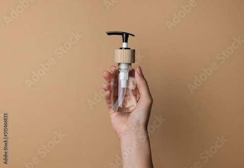 Woman holding bottle of cosmetic product on beige background, closeup