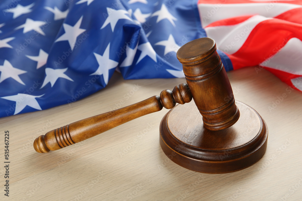 Judge's gavel and American flag on light wooden table