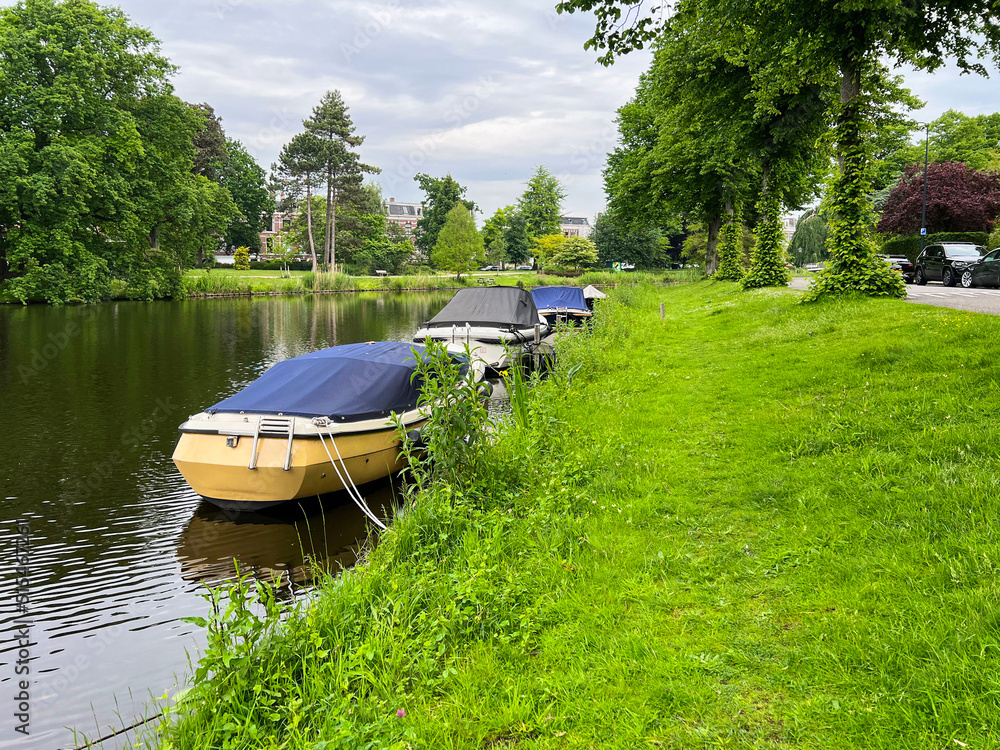 Beautiful view of city canal with moored boats surrounded by greenery