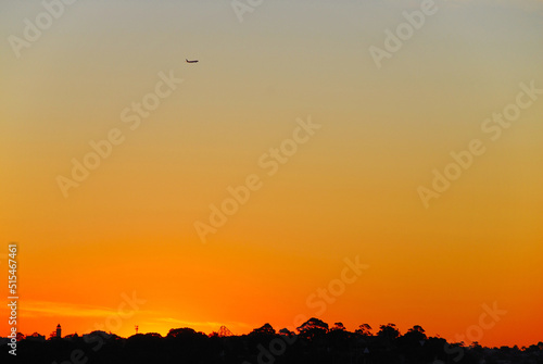 An Airplane Departing On An Evening Flight With An Orange Colored Sunset Behind It.