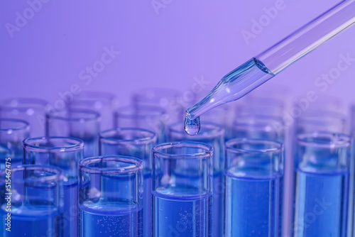 Dripping reagent into test tube on violet background, closeup with space for text. Laboratory analysis