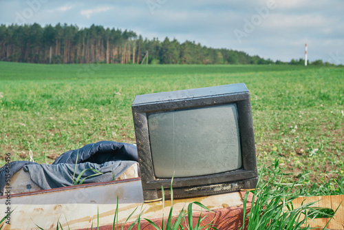 Old TV on the field near fores green grass photo