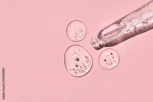 Close up of pipette with fluid collagen and hyaluronic acid, hydration skin with shadows on pastel pink background on sunlight. Cosmetology, dermatology concept. photo