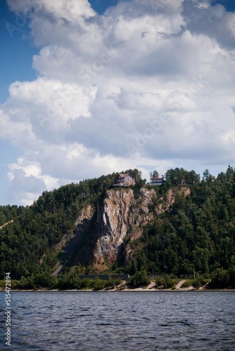 A red house in the clouds on top of a cliff. 