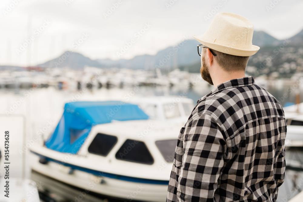 Rear view man wearing hat with yachts and marina background with copy space and empty place for advertising