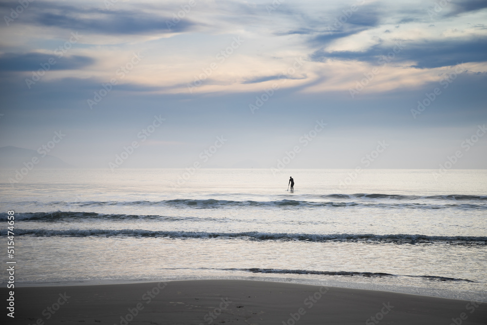 paddle boarder on the beach at sunrise