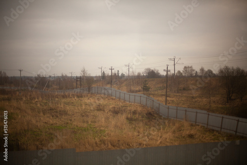 Fence in field. Fenced empty field. Steel fence is long.