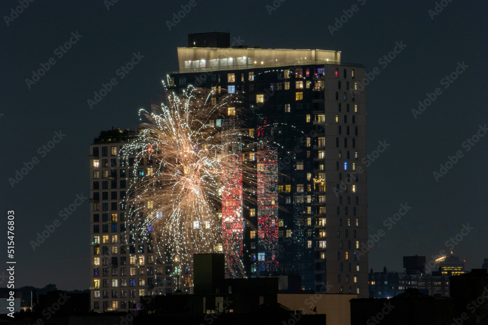 Fireworks going off in in front of luxury buildings in Brooklyn, NY with cityscape in background