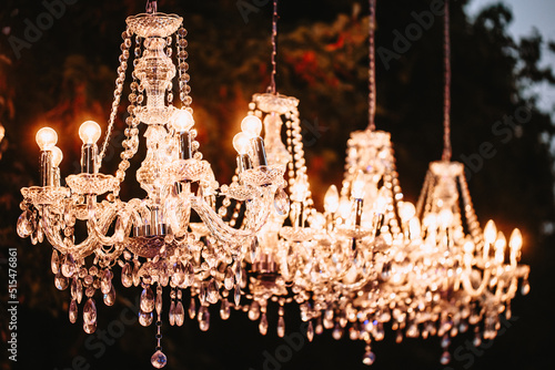 Crystal chandeliers glow in the evening in the park as a decoration.
