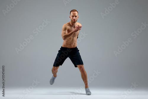 Developing endurance. Male athlete in motion isolated over gray studio background. Maintaining health and strength. Concept of sport  healthy lifestyle  motion