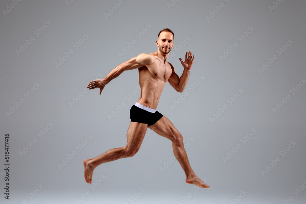 Full length portrait of a confident young sportsman shirtless jumping isolated over white background