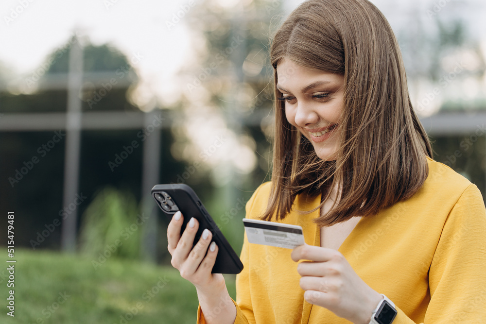 Happy caucasian woman buying things online using smartphone and credit card enjoying shopping in internet. Positive young girl purchasing goods on web, making remote payment. Happy caucasian woman buying things online using smartphone and credit card enjoying shopping in internet. Positive young girl purchasing goods on web, making remote payment.