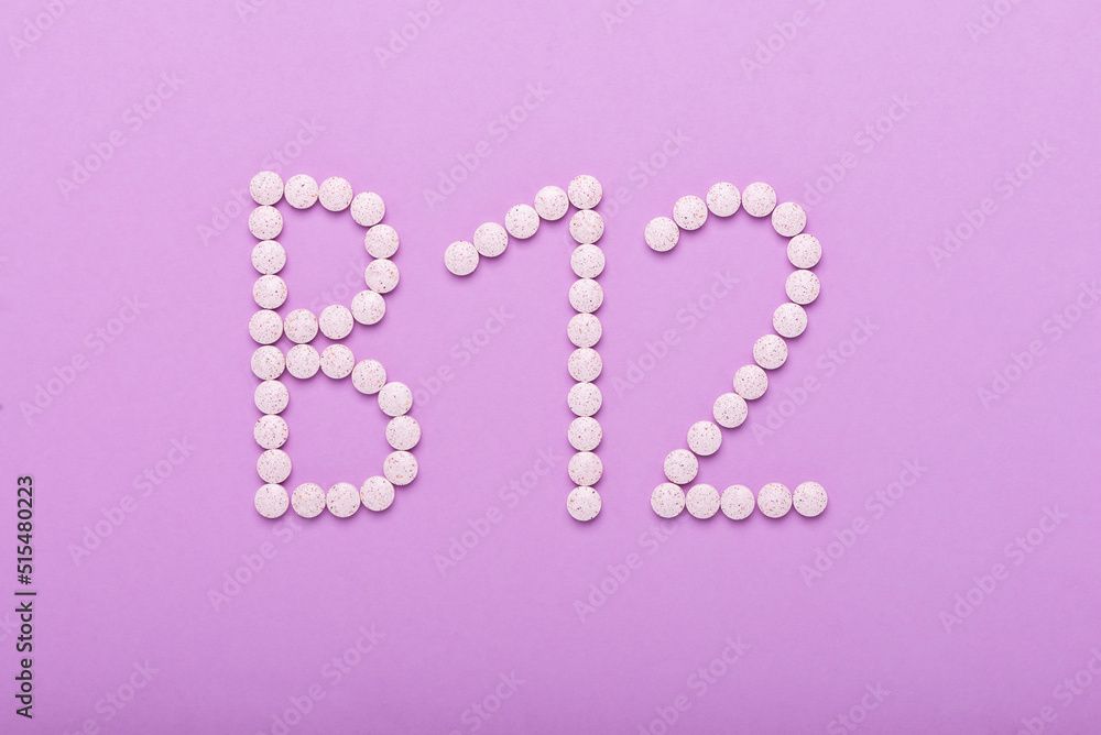 Vitamin B12 pills formed in a word 'B12' over pink background, top view
