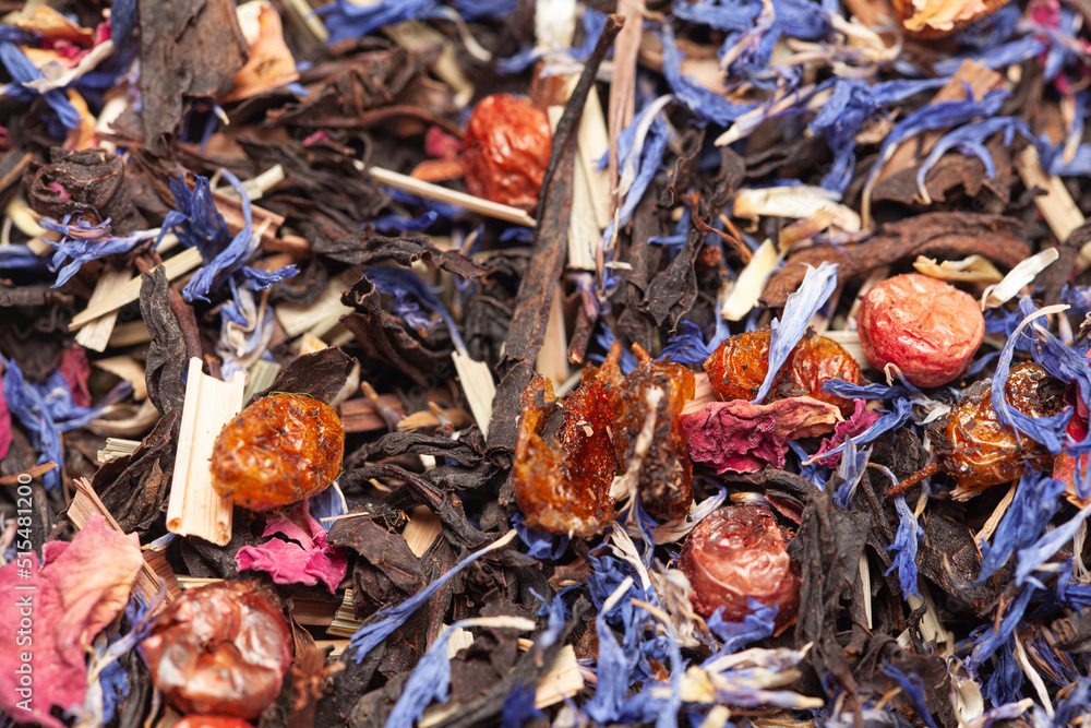 black tea with lemongrass, currant berries, sea buckthorn berries, rose petals, cornflower petals background top view