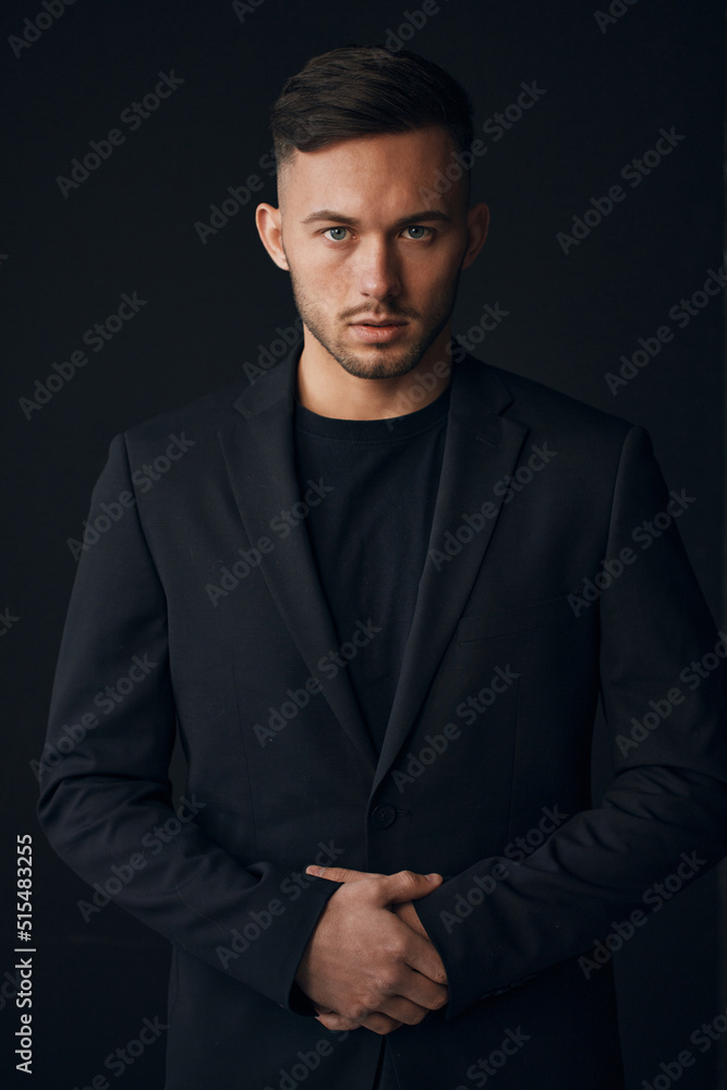 Modelling snapshots. Narcissistic self-confident tanned attractive handsome man in classic suit jacket looks at camera posing isolated in over black studio background. Fashion offer. Copy space for ad