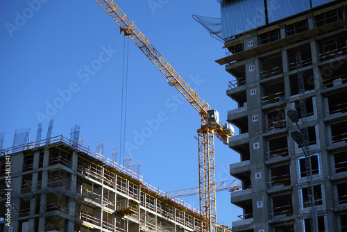 Construction of a modern residential building. An unfinished house and a tower crane against a clear blue sky. © Орлов Александр