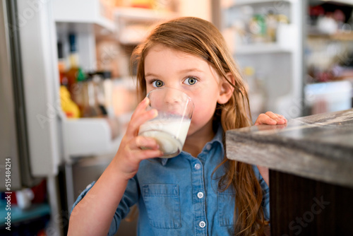 Fotografía beautiful girl drinks milk on the glass in the kitchen