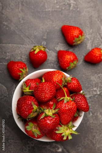 Fresh ripe strawberries in a plate on a black texture background.Vegetarian organic berry.Healthy food.Vitamins.Copy space.Place for text