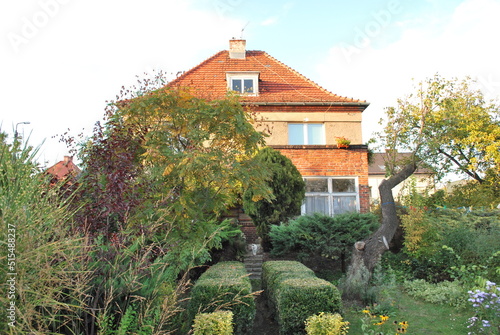 a wooden truss on the wall of the building is covered with climbing trees, you can see a green watering can