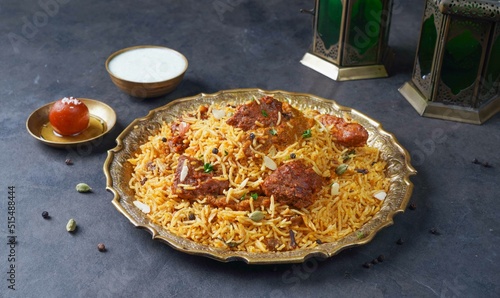 Indian spicy Beef Biryani with raita and gulab jamun Served in a dish side view on grey background