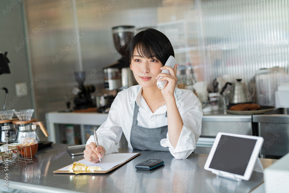 カフェ 電話をする女性スタッフ カフェ 電話をする女性スタッフ