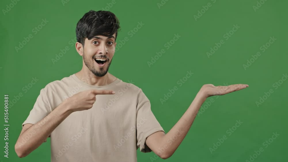 Indian man smiling recommend blank area over green background holds copy space on hand advertise points at empty place arabic guy using mockup for promo advertisement thumb up finger best choice sign Indian man smiling recommend blank area over green background holds copy space on hand advertise points at empty place arabic guy using mockup for promo advertisement thumb up finger best choice sign