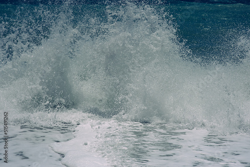 Blue waves crashing on the beach with white spray and foam. Dangerous stormy sea. Beautiful textured coastline background. 