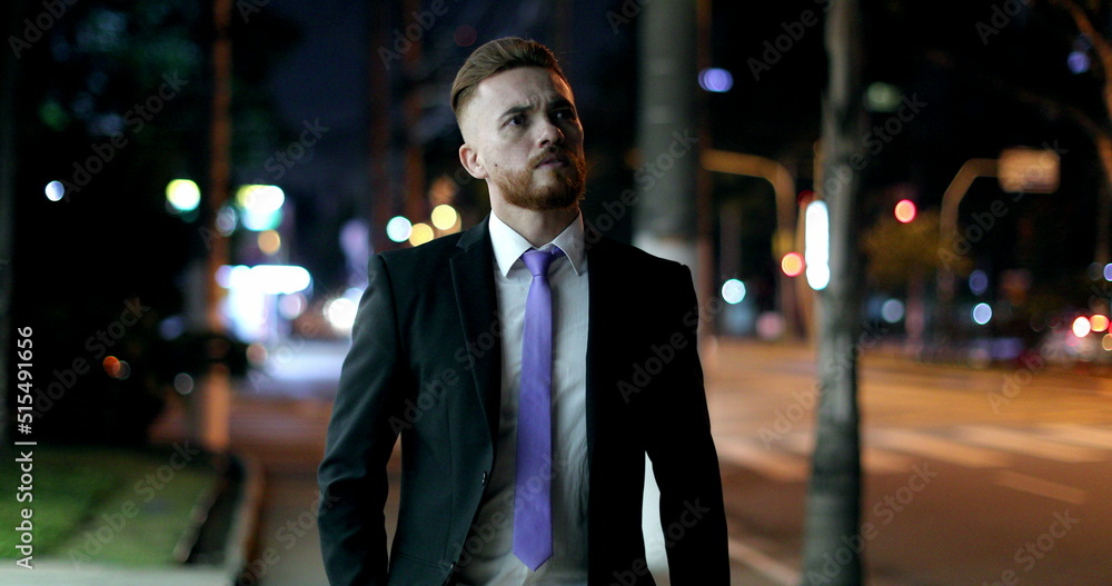Pensive worried business man walking at night in city