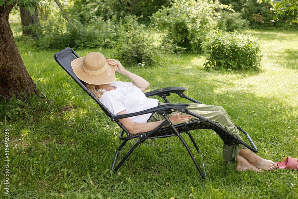 Woman reading a book in garden recliner chair. Summer vacation in the