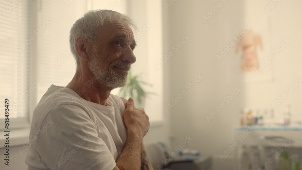 Elderly man holding shoulder after vaccine in clinic closeup. Prevention concept Elderly man holding shoulder after vaccine in clinic closeup. Prevention concept