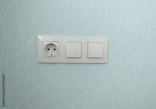 isolated white beige switch and socket on a light wall. aesthetics of electrics, repair, security, interior, design. place for text